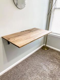 a wooden table sitting on top of a carpeted floor next to a wall mounted clock