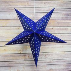 a blue paper star hanging from a string on a wooden wall with polka dotes