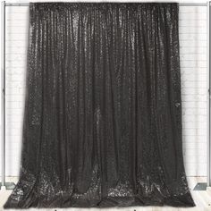 a black curtain hanging from the side of a brick wall in front of a white brick wall