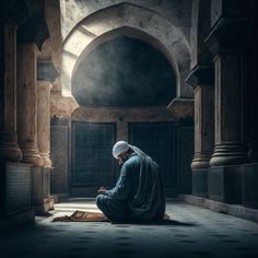 a man sitting on the floor in front of an archway looking at his cell phone