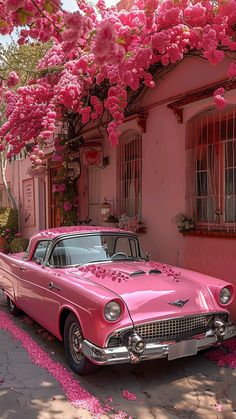 an old pink car parked in front of a house with flowers on the roof and windows