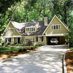 a car is parked in front of a house with trees and shrubs around it on the driveway