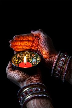 a woman's hands holding a small bowl with a lit candle in the middle