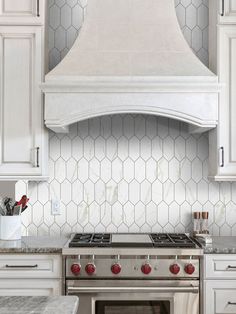 a stove top oven sitting inside of a kitchen next to white cabinets and counter tops