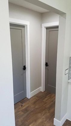 an empty room with white walls and wood flooring is pictured in this image, there are two doors leading to another room