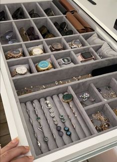 a person is holding an open drawer full of jewelry