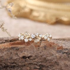 two gold rings with white stones on them sitting on top of a rock next to a mirror