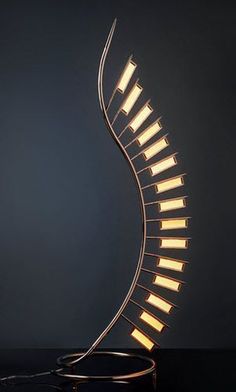 a metal spiral lamp on a black surface with light coming from the top and bottom