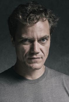 a man with curly hair is looking at the camera and has an intense look on his face