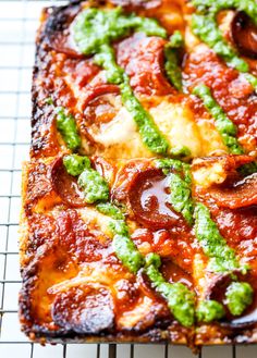 a square pizza sitting on top of a cooling rack covered in sauce and toppings