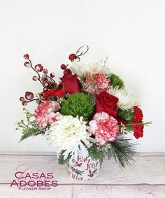 a white vase filled with red and white flowers