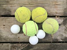 four tennis balls sitting next to each other on top of a wooden table with white balls