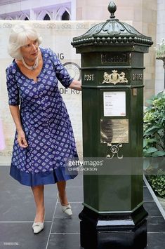 the queen of england standing next to a post box