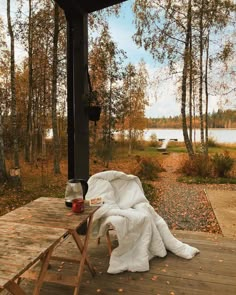 a picnic table with a blanket on it next to a lake