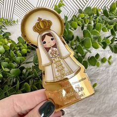 a hand holding up a gold and white sticker with an image of a bride on it