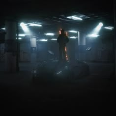 a man standing on top of a car in a dark room with lights shining down