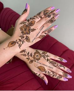 two hands with henna designs on them, one is purple and the other is brown