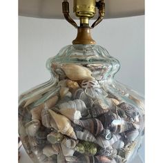 a glass vase filled with sea shells under a lamp