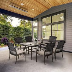 an outdoor dining table and chairs on a patio with wood ceilinging, windows, and sliding glass doors