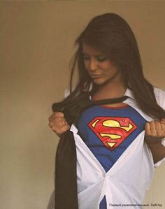 a woman is holding up a t - shirt with a superman logo on it and a tie around her neck