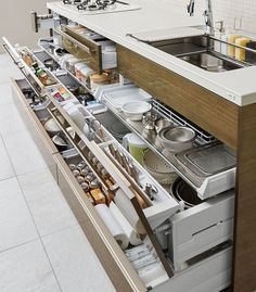 an open drawer in the middle of a kitchen with pots and pans on it