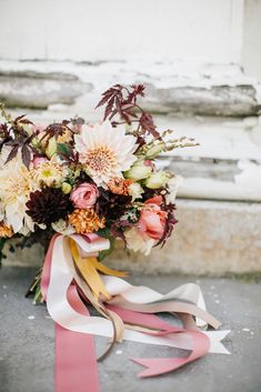 a bouquet of flowers sitting on the ground next to a ribbon tied around it's neck