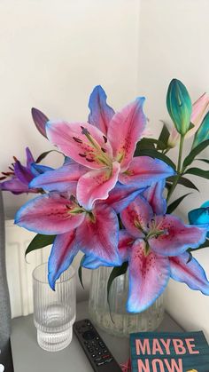 pink and blue flowers sit in a vase on a table next to a remote control