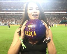 a woman is holding a soccer ball in front of her face at a sporting event