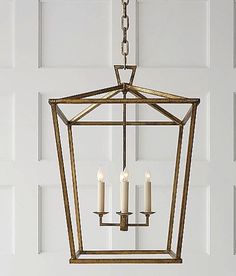 a light fixture hanging from the ceiling in front of a white door with three candles on it