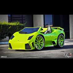 a bright green sports car parked in front of a building with its doors open and the top down