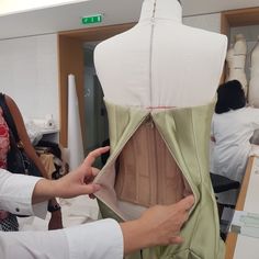 a woman is working on a mannequin dress