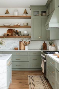 a kitchen with green cabinets and white counter tops, wooden flooring and open shelving