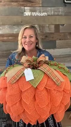 a woman standing next to a large orange pumpkin shaped door hanger with a bow on it