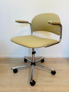 an office chair sitting on top of a hard wood floor next to a white wall