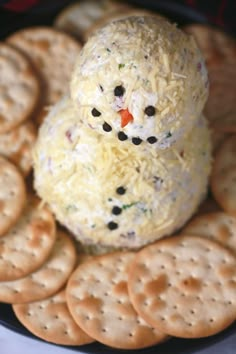 a snowman made out of crackers sitting on top of a plate filled with crackers