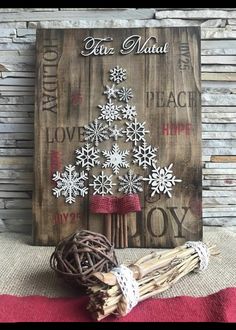 a wooden sign with snowflakes on it next to cinnamon sticks and a ball of yarn