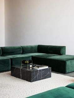 a large green couch sitting on top of a white rug next to a coffee table