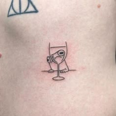 a woman's stomach with a wine glass tattoo on it