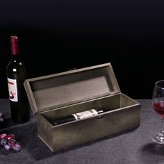 a bottle of wine sitting next to a wooden box with a corkscrew in it