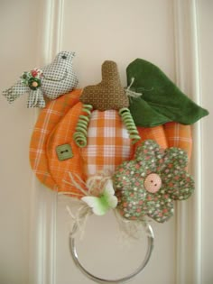 an orange and white wreath is hanging on the front door with three fabric flowers in it