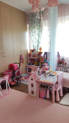 a child's bedroom with pink furniture and toys on the floor in front of a window