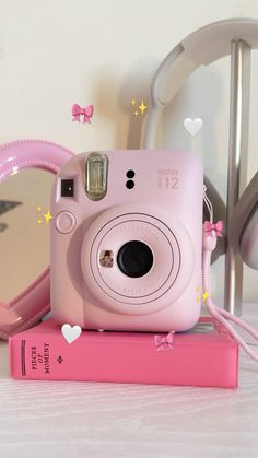 a pink camera sitting on top of a book next to a pair of heart shaped glasses