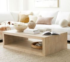 a living room with a white couch, coffee table and books on the end tables