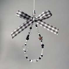 a black and white ribbon hanging from a metal ornament on a gray background