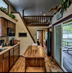 a kitchen with wooden cabinets and an open staircase leading to the second floor above it