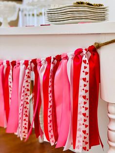 red, white and pink ribbons are hanging from a table