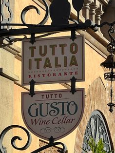 a sign hanging from the side of a building that says tutto italia restaurante and gusto wine cellar