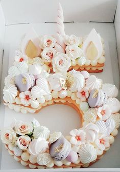 a cake shaped like the letter c is decorated with seashells and flowers in a box