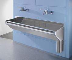 a stainless steel sink with two faucets on the side and blue cabinets behind it