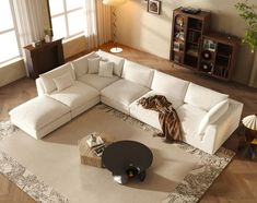 a living room with a large white sectional couch and coffee table on the floor in front of it